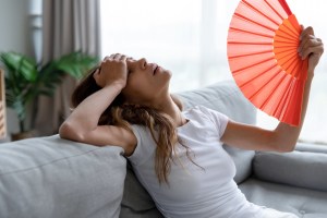 Exhausted girl using paper waver, suffering from hot summer weather. - stock photo