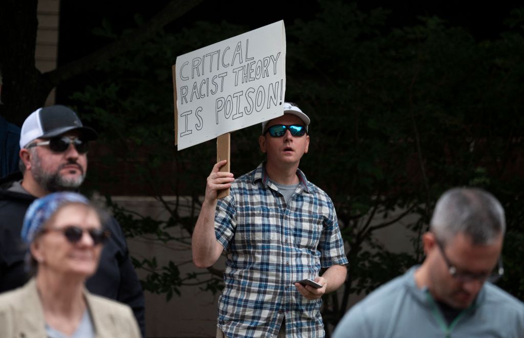 A man holds up a sign during a rally against "critical race theory" (CRT) being taught in schools at the Loudoun County Government center in Leesburg, Virginia on June 12, 2021.