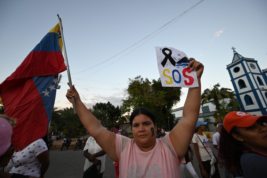 A woman holds up a Venezuelan flag as relatives and friends of 28 Venezuelan migrants who died in the wreck of a boat transporting them to Trinidad and Tobago protest at the main square in Venezuela in December, 2020.