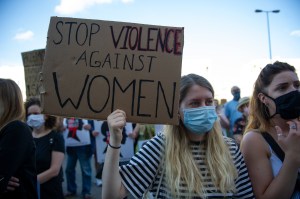 Demonstrators wearing protective face masks hold placards during an anti-domestic violence protest on July 24, 2020 in Warsaw, Polan