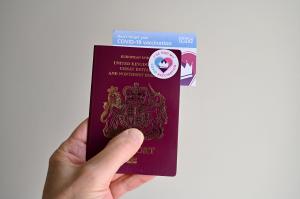 A man holding up his vaccine certificate and his passport