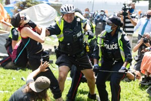 A police officer grabs woman by neck