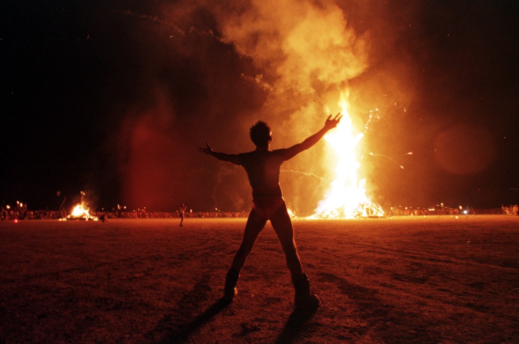 A man standing in front of the burning man