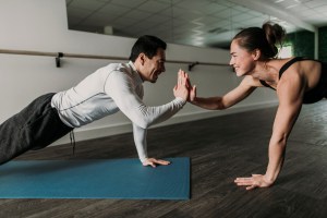 male and female friends high five while doing pushups at gym