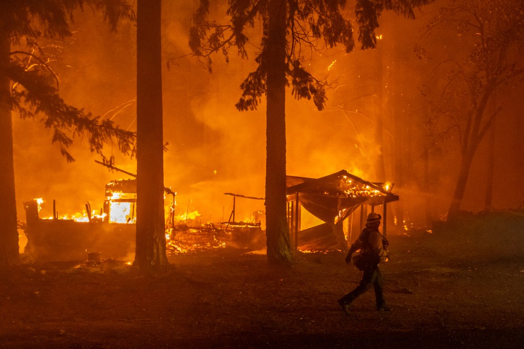 A firefighter monitors a fire as multiple structures burn in the Indian Falls neighborhood during the Dixie Fire near Crescent Mills, California, U.S., on Saturday, July 24, 2021.