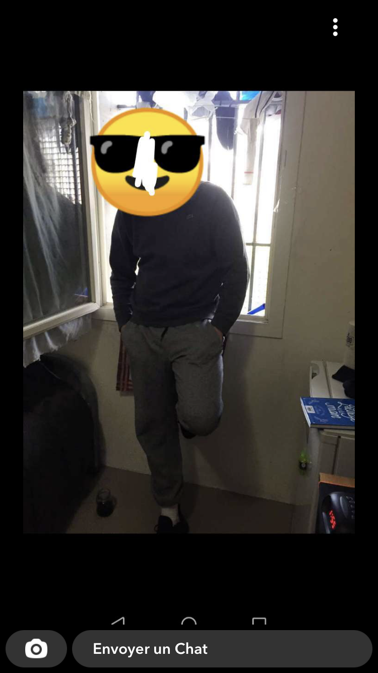 UnTikTolard – man in gray sweatpants and a blue jumper, standing in front of a barred window with laundry hanging on it. His face is covered by an emoji.