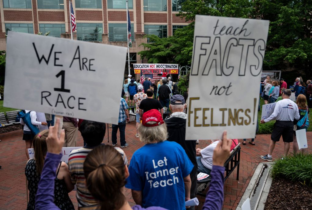 People hold signs during a rally against critical race theory being taught in schools, at the Loudoun County Government Center in Leesburg, Virginia, on June 12, 2021.