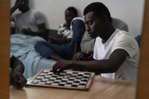 A Senegalese migrant plays checkers in his room in the Holiday Club Puerto Calma hotel in Puerto Rico de Gran Canaria, Spain, 2nd of April, 2021. Photo: AP Photo/Renata Brito