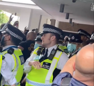 A police officer looks on as protesters surround him at Television Centre in West London. ​Screengrab: @PaulBrown_UK on Twitter