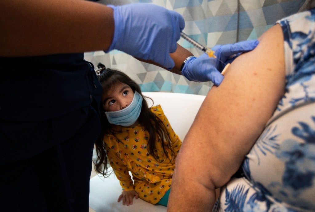 Monserat Ramos, 3, keeps a close eye on the needle as both of her grandparents are vaccinated at a clinic run by MLK Community Healthcare (MLKCH) on Friday, March 5, 2021 in South Los Angeles, CA. (Francine Orr / Los Angeles Times via Getty Images)​