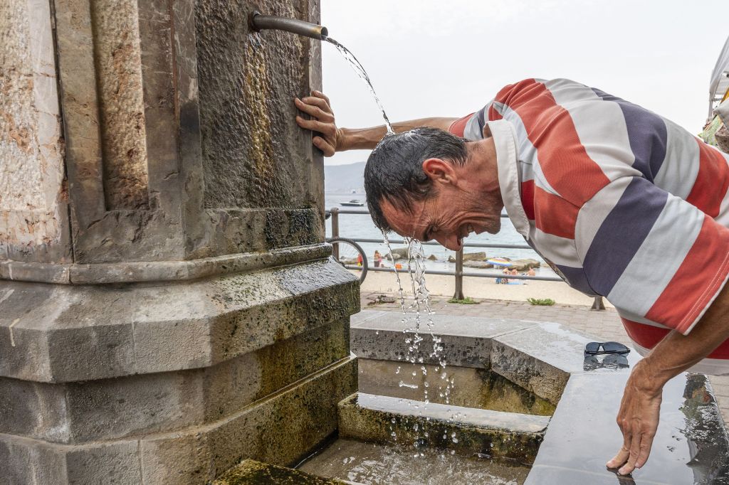 A man refreshes himself in a fountain during a hot summer day in Messina, on August 11, 2021. Photo: Giovanni ISOLINO / AFP