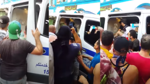 ​Screenshots of video showing a crowd of people pulling Djamel Ben Ismail​ out of a police vehicle in Algeria and beating him.