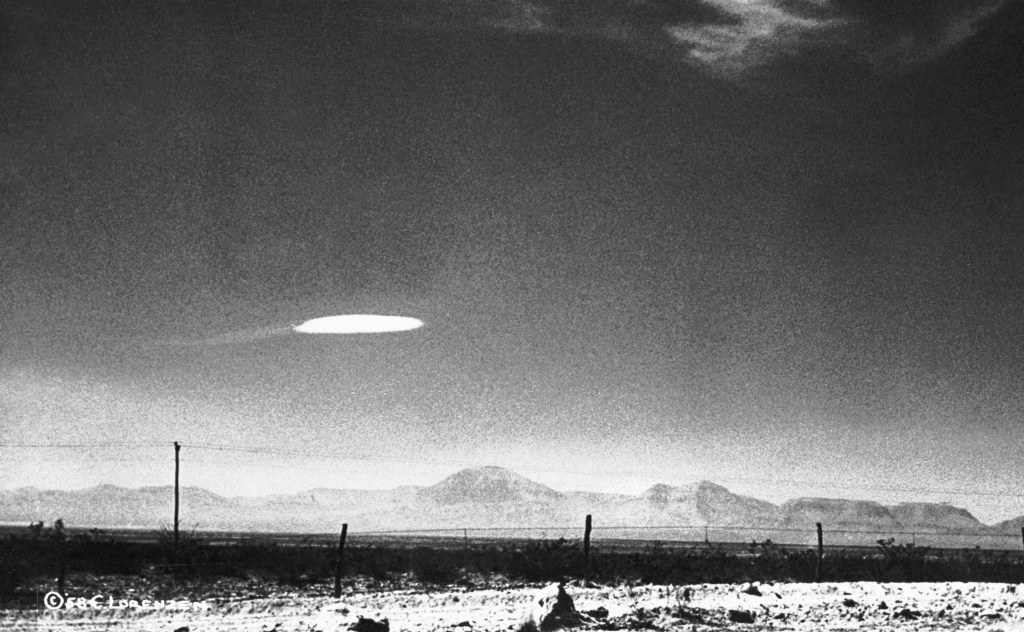 Photo shows a disc-shaped blur in the sky over the mountains of New Mexico.