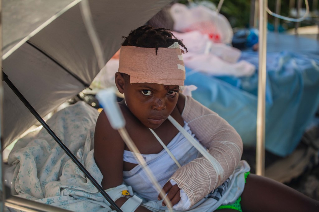 A boy is tended to outside Les Cayes General Hospital after a 7.2-magnitude earthquake struck Haiti on August 15, 2021.