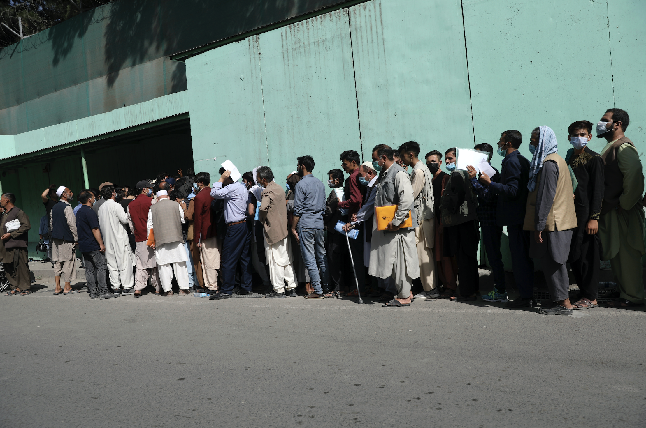 Afghans wait in long lines for hours to get visas in front of the Iranian embassy, in Kabul, Afghanistan on Sunday, Aug. 15, 2021.