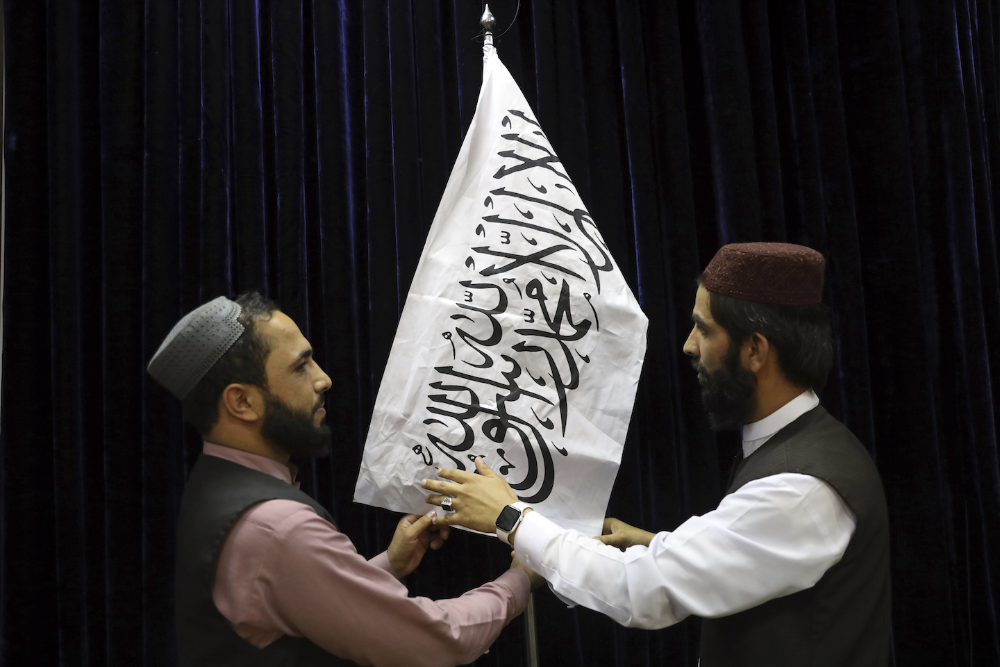 men arrange taliban flag