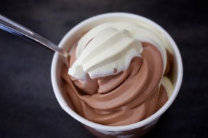 Chocolate and vanilla soft serve ice cream in a cup with a plastic spoon.