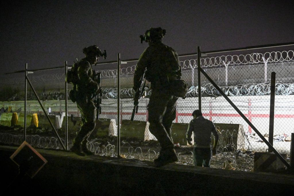 British and Canadian soldiers stand guard as Afghans wait outside the foreign military-controlled part of the airport in Kabul, hoping to flee the country following the Taliban's military takeover of Afghanistan. Photo: by WAKIL KOHSAR / AFP