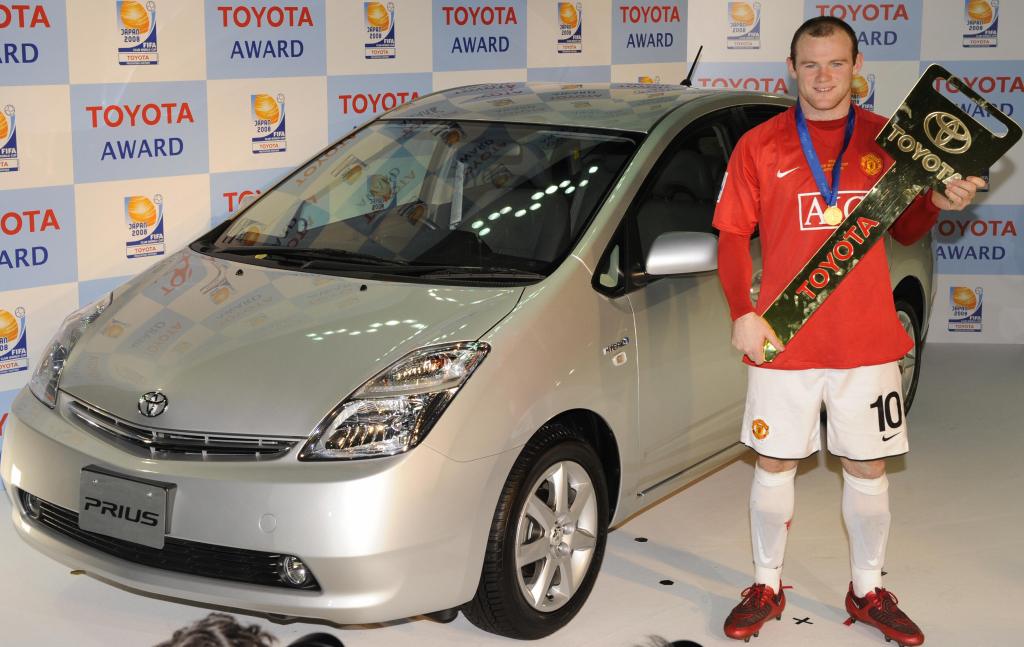 Wayne Rooney standing next to a Prius