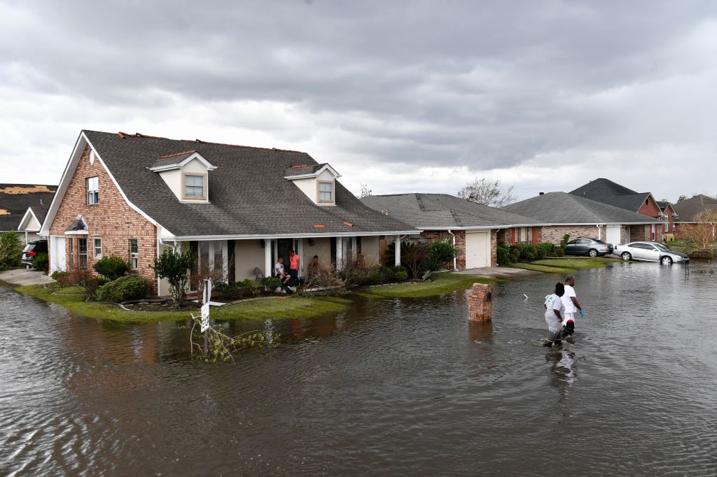 Residents wade through flood waters after their neighborhood flooded in LaPlace, Louisiana on August 30, 2021 in the aftermath of Hurricane Ida.