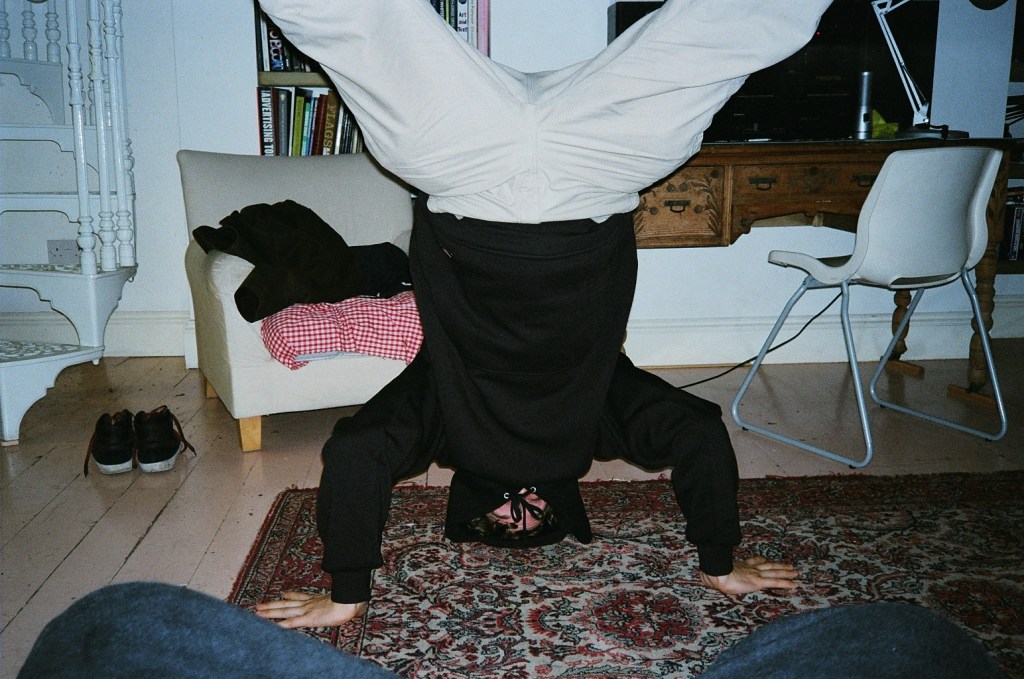 Irresponsible flatmate standing on his head in a rented houseshare