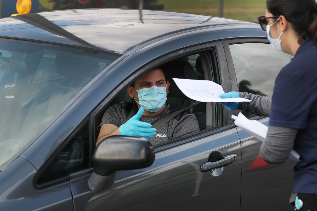 A person in their car arrives to receive an unemployment application being given out by City of Hialeah employees in front of the John F. Kennedy Library on April 08, 2020 in Hialeah, Florida. (Joe Raedle/Getty Images)​