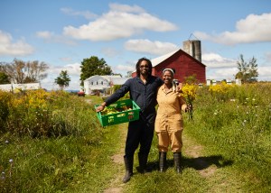 Arian Rivera, 39, and Ashanti Williams, 32, of Black Yard Farm Cooperative pose with a crate of peppers and wild flowers picked in a field nearby in August 2021.