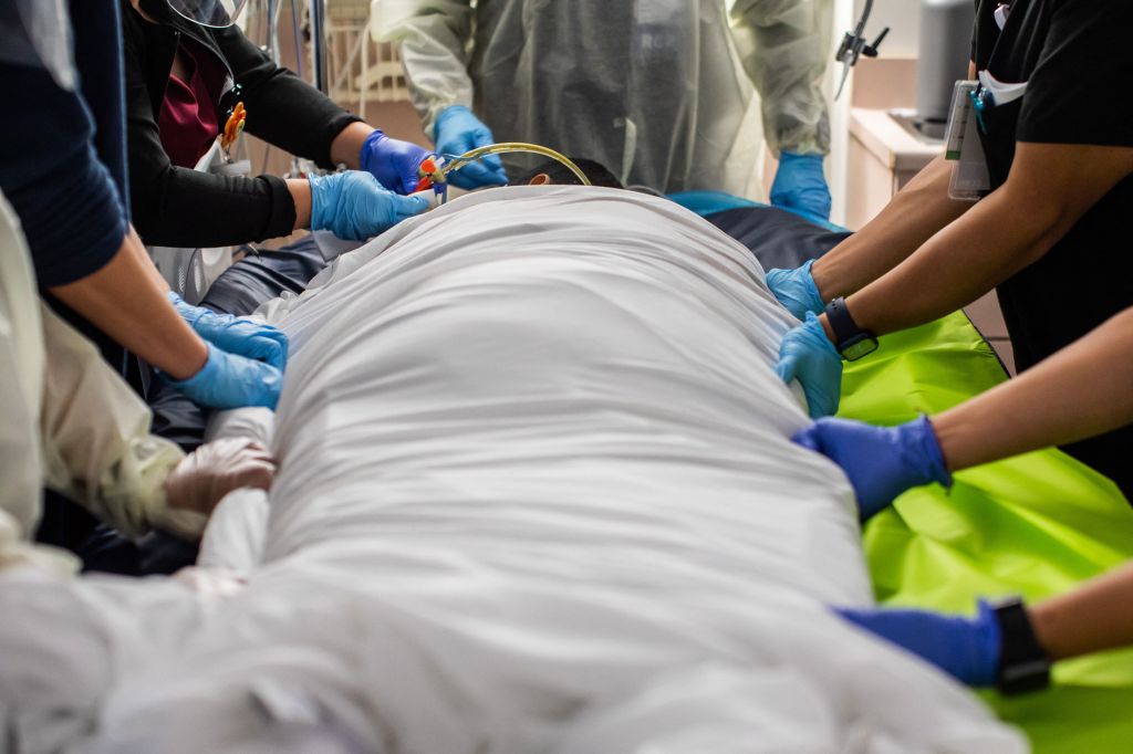 Health care workers attend to a patient with COVID-19 as they prepare to turn the 45 year old unvaccinated patient from his stomach onto his back at the Cardiovascular Intensive Care Unit at Providence Cedars-Sinai Tarzana Medical Center in Tarzana, Calif