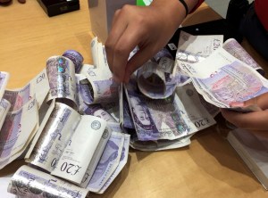 Una persona cuenta fajos de billetes de £20