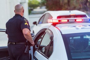 Policeman pulls over a driver for speeding, getting out of police car to write a traffic ticket. (