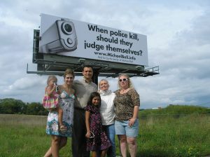 ​Michael Bell Sr. and his family stand in front of a billboard for MichaelBell.info.