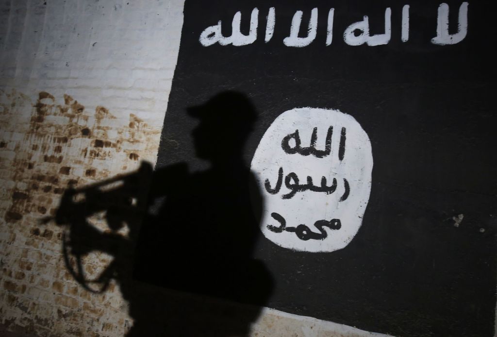 A member of the Iraqi forces walks past a mural bearing the logo of the Islamic State (IS) group in a tunnel that was reportedly used as a training centre by the jihadists, on March 1, 2017