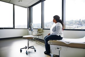 Side view of female patient sitting on bed in hospital