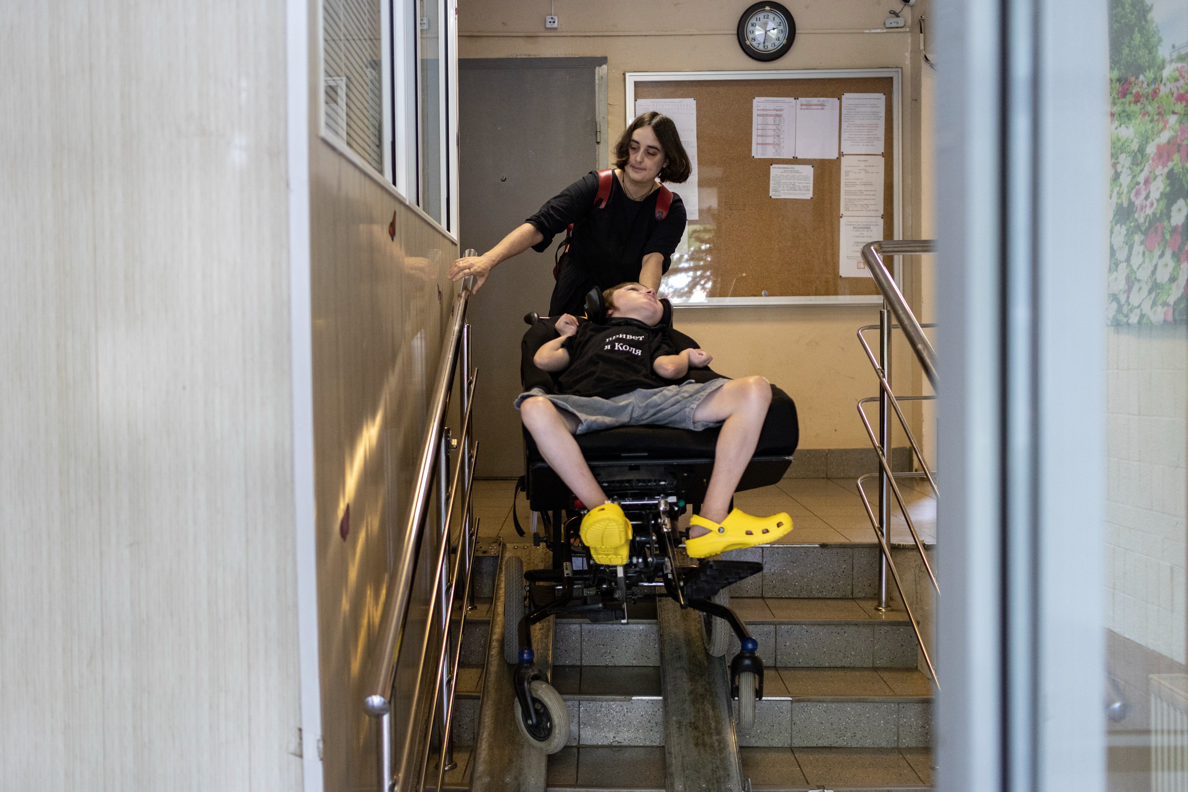 LIDIA MONIAVA, 33, THE FOUNDER OF THE HOUSE WITH THE LIGHTHOUSE CHILDREN’S HOSPICE, PUSHES KOLYA IN A SPECIALISED WHEELCHAIR DOWN THE STAIRS AT AN ENTRANCE OF AN APARTMENT BUILDING IN MOSCOW, RUSSIA.