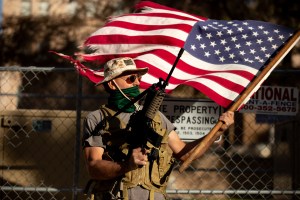 PHOENIX, AZ - JANUARY 20: A supporter of President Trump holds a flag and gun outside the Arizona State Capitol on January 20, 2021 in Phoenix, Arizona. (Courtney Pedroza for the Washington Post)​