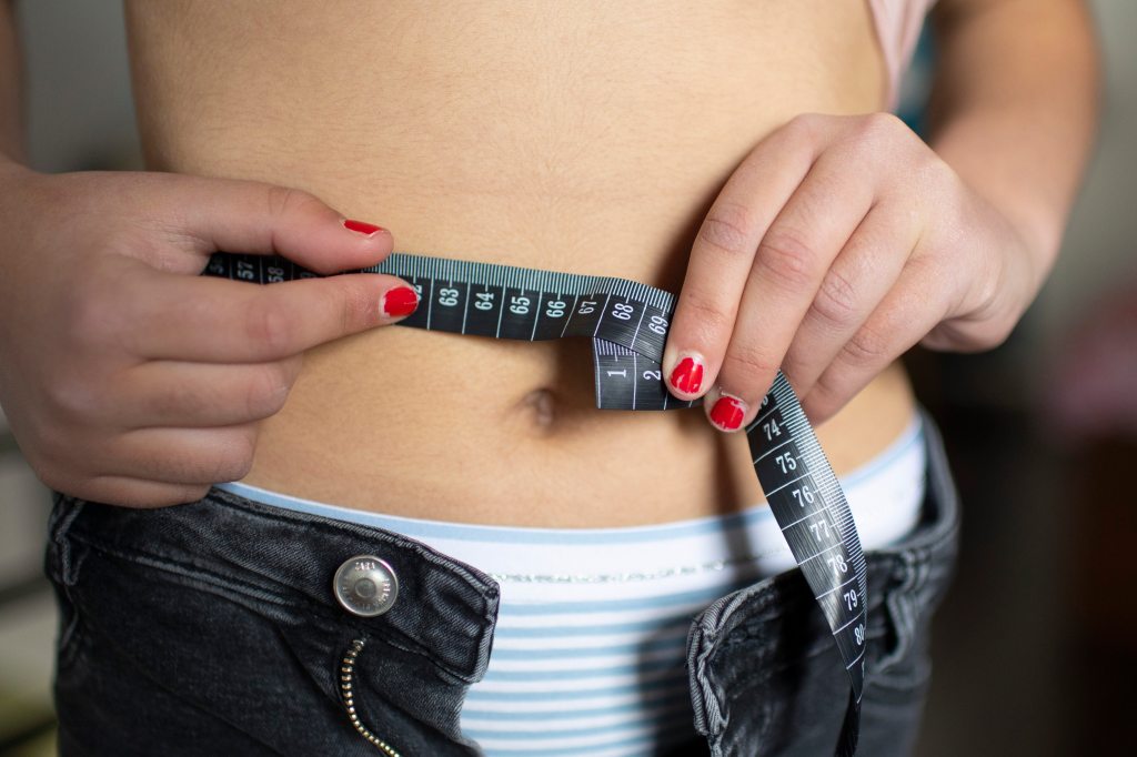 In this photo illustration a girl measures her abdominal girth on April 16, 2021 in Bonn, Germany. (