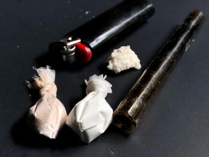 Cocaine, heroin, and crack with paraphernalia over a black background. (Cappi Thompson​/Getty Images)