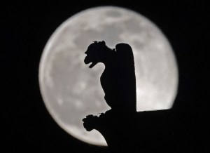 ​A gargoyle is illuminated by the full moon at Notre-Dame cathedral, the headquarters of the Catholic church in France. Photo: THOMAS COEX/AFP via Getty Images​