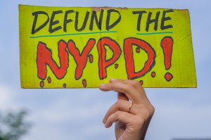 A participant holding a Defund NYPD sign at the protest.