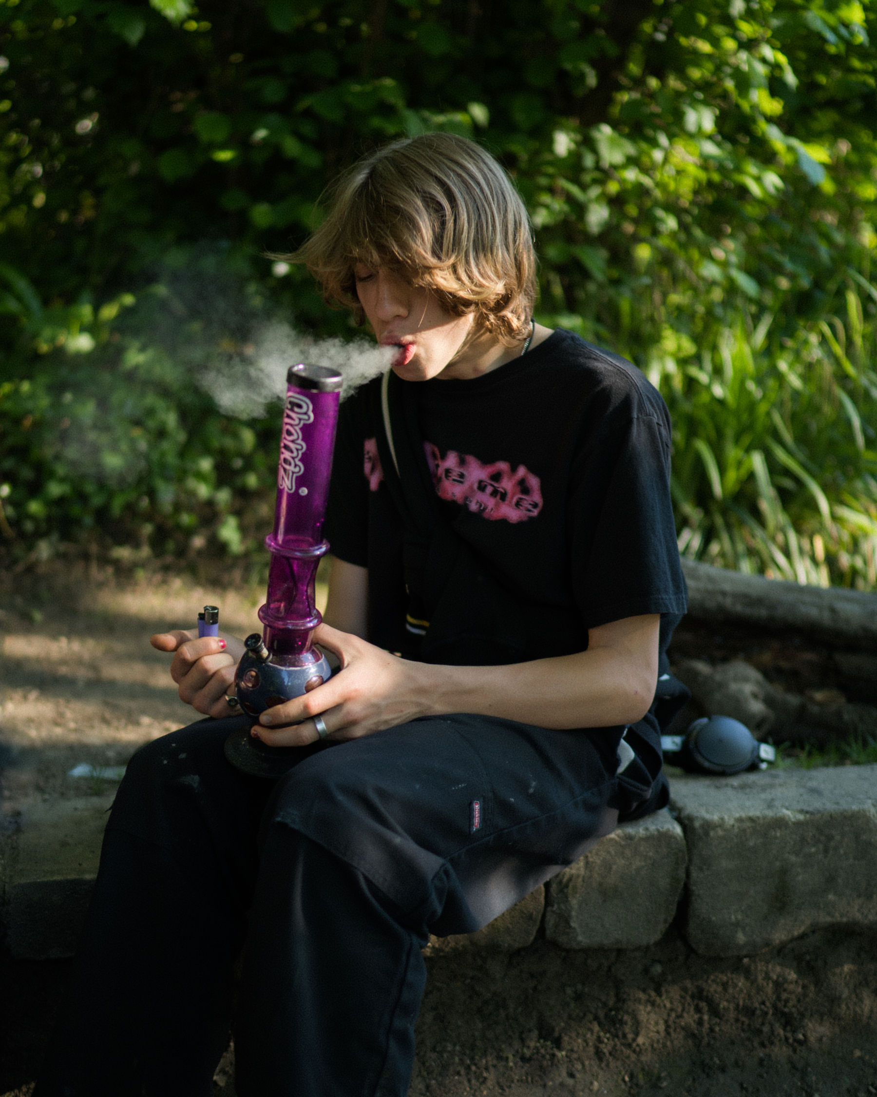 A dirt bike rider takes a bong hit.