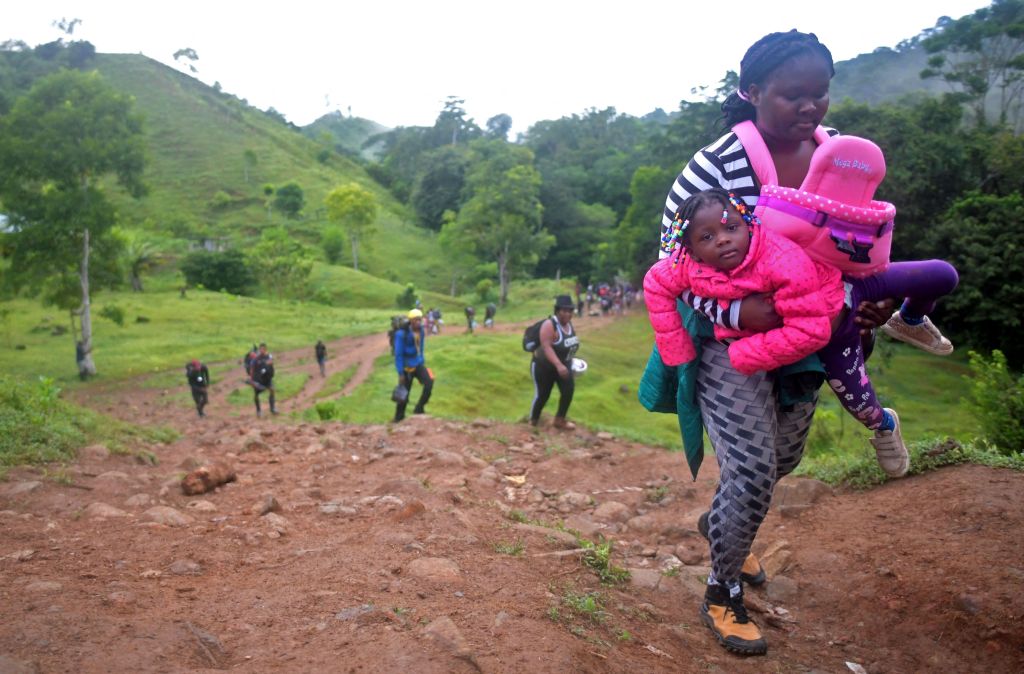 A Haitian migrant woman carries a girl as they cross the jungle of the Darien Gap, near Acandi, Choco department, Colombia, heading to Panama, on September 26, 2021, on their way trying to reach the US.