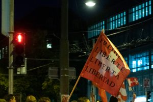 Eine Schweizerfahne wird in der Schweiz bei einer Demonstration gegen die Coronamaßnahmen der Luft geschwenkt, auf ihr steht der Schriftzug: Freiheit Liberté Liberta.