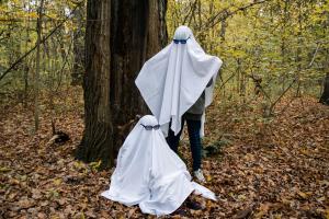 Two people dressed as ghosts with white bed sheets and sunglasses