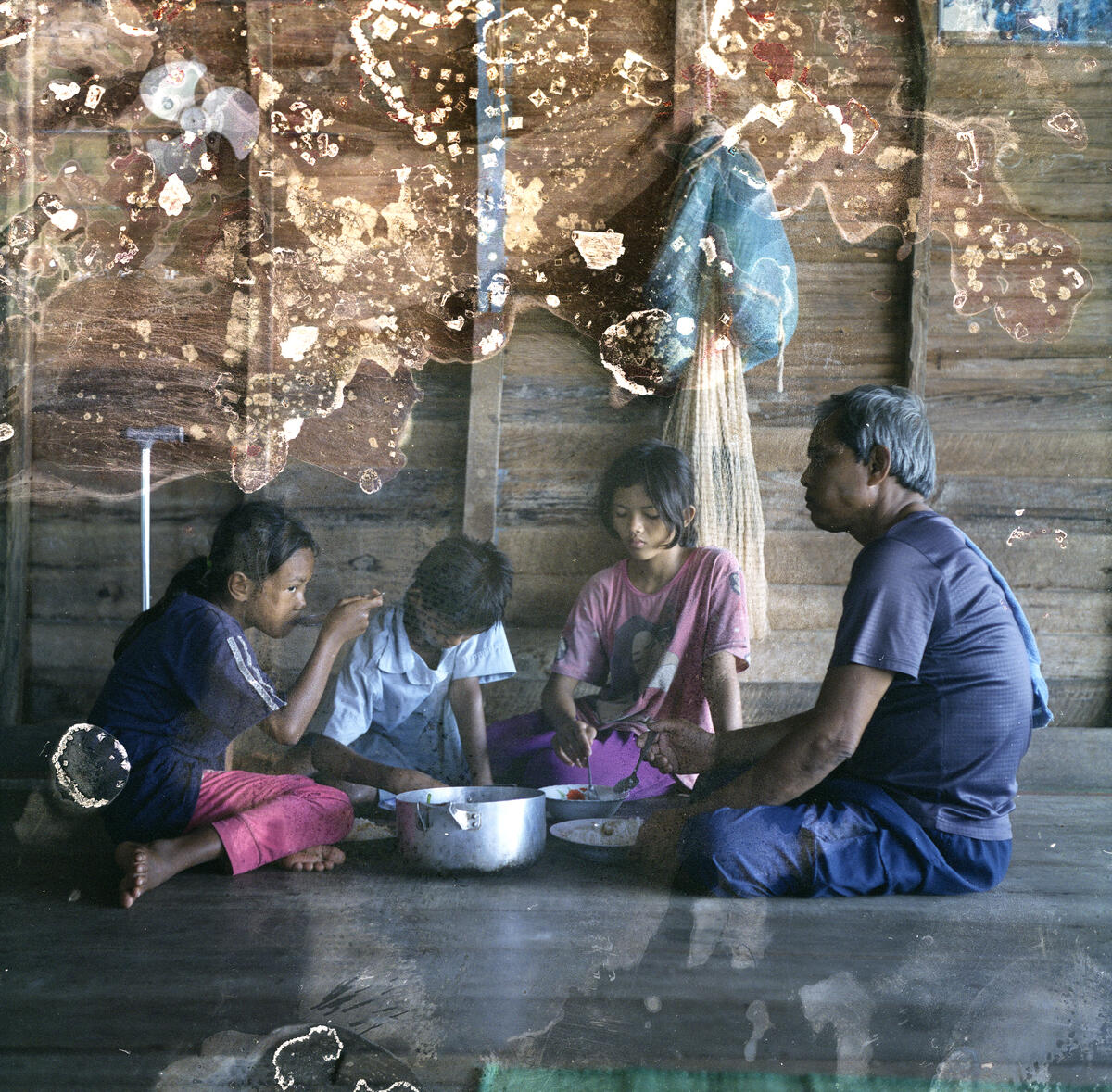 MengHy having lunch with his siblings and grandfather in their floating house. Image: Lim Sokchanlina / Save the Children 