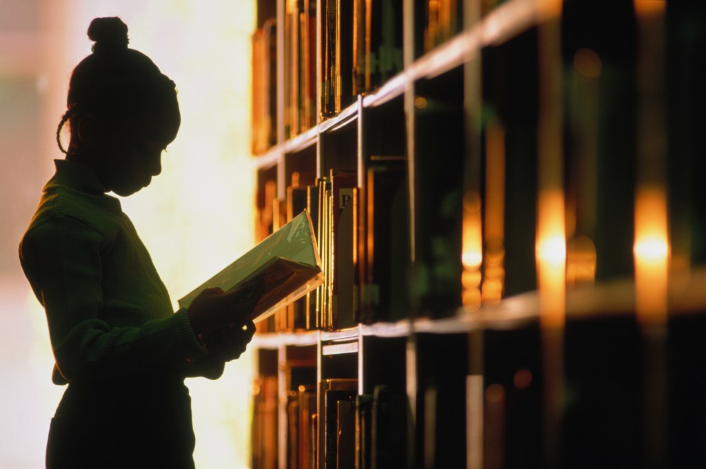 A young girl reading in a library.