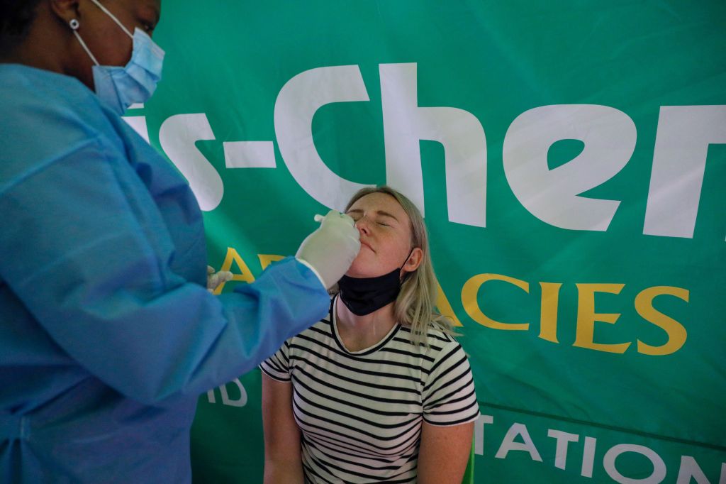 A healthcare worker conducts a polymerase chain reaction (PCR) Covid-19 test on a traveller at OR Tambo International Airport in Johannesburg