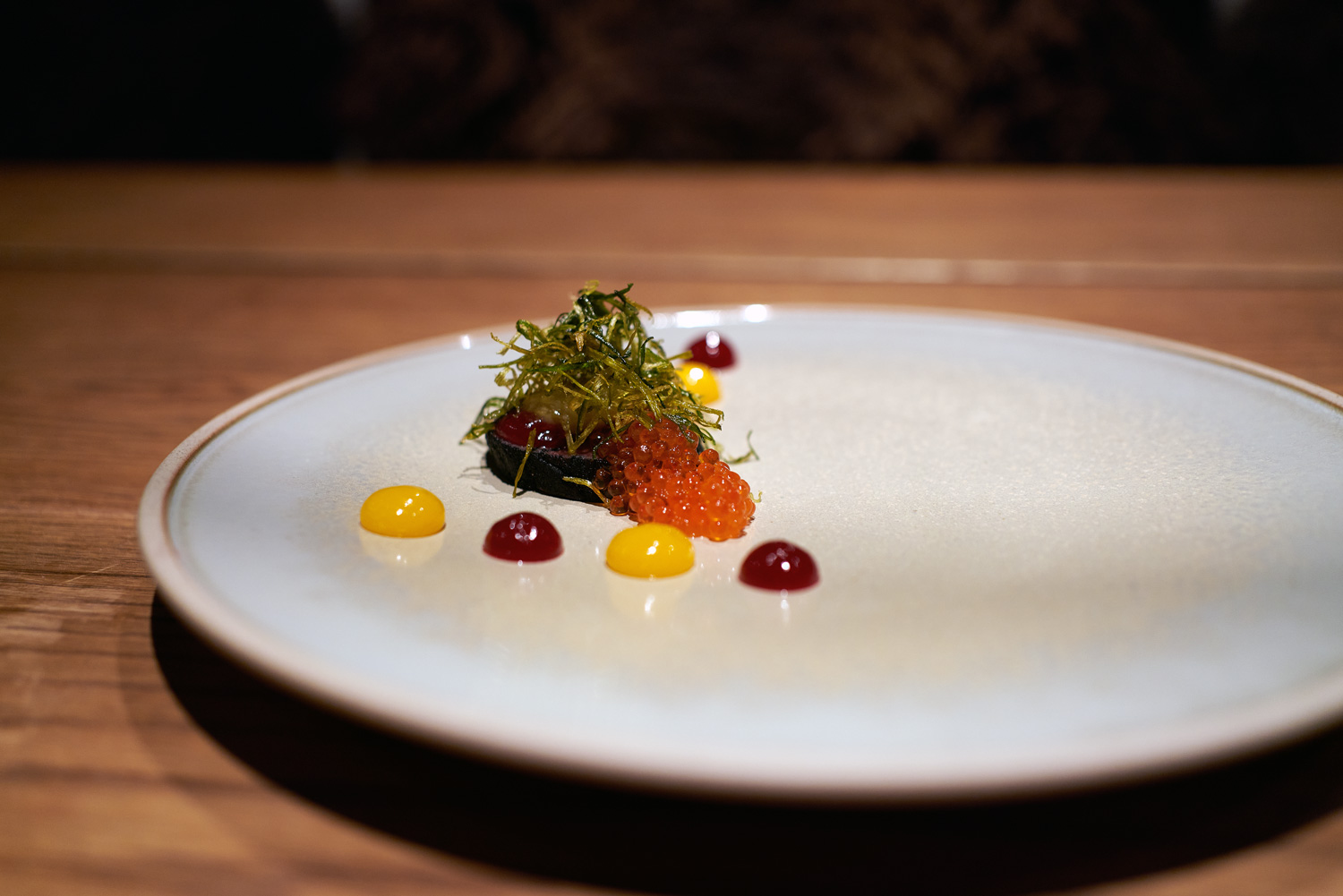 Arctic cuisine, Svalbard, Nick Casini - Photo of orange caviar on a white plate, surrounded by four red and yellow blobs of liquid,