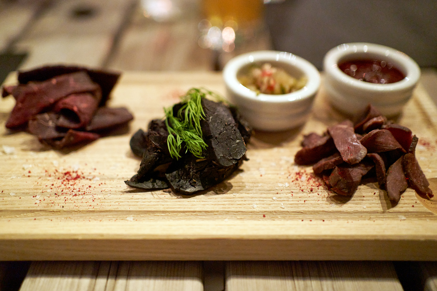 Arctic cuisine, Svalbard, Nick Casini - Photo of three cuts of sliced red meat on a wooden board.