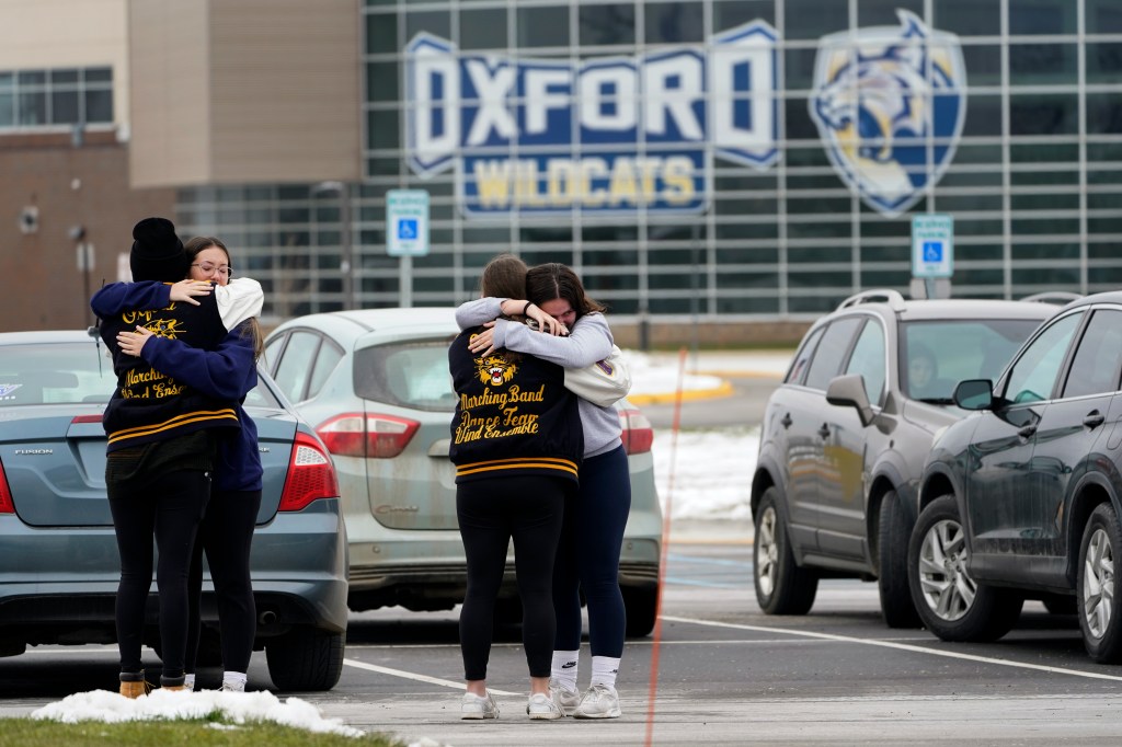 Students hug at outside Oxford High School in Oxford, Mich., Wednesday, Dec. 1, 2021.