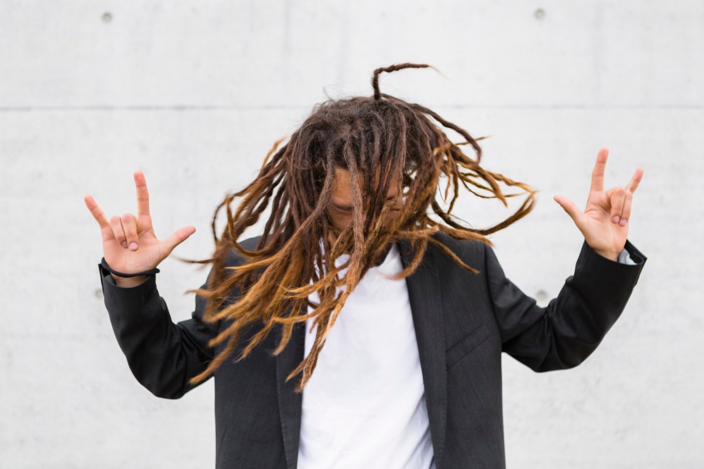 Young businessman tossing his locs and showing the rock 'n' roll sign